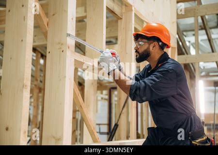 Measuring the piece. Male carpenter working with wooden materials in a professional workshop. Stock Photo