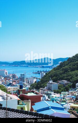 A high-angle, vertical shot featuring the iconic colorful terraced houses of Gamcheon Culture Village under a clear blue sky. The vibrant pastel color Stock Photo
