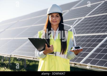 Female solar engineer inspecting photovoltaic panels during outdoor maintenance work. Stock Photo