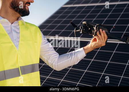 The drone is in the hand. Male solar engineer examining photovoltaic panels at a power station. Stock Photo
