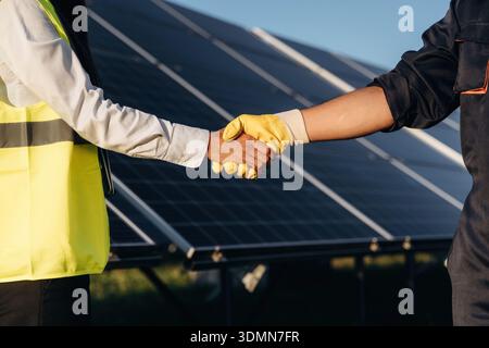 Two solar engineers standing together at a photovoltaic field, in bright safety vests. Stock Photo