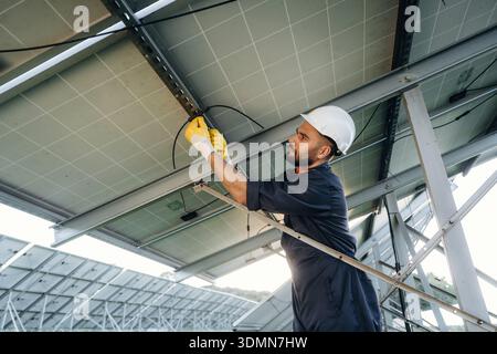 Strong construction, under the surface, installation. Male solar engineer examining photovoltaic panels at a power station. Stock Photo