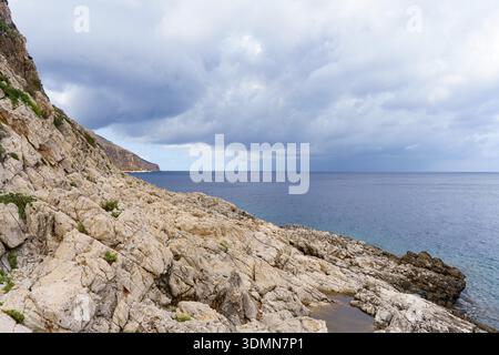 A dramatic panoramic view of the rugged, pale limestone cliff area between Cala Nucidda and Cala Stella Marina on Levanzo Island, capturing the raw ge Stock Photo