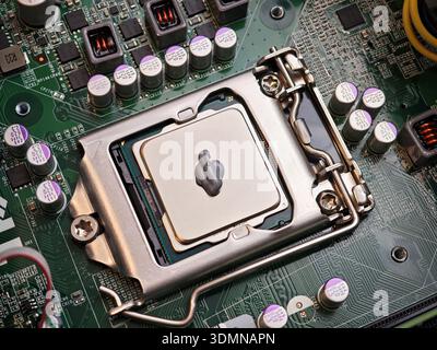 Top view closeup of desktop motherboard with CPU in socket and blob of thermal paste on heat spreader, PC repasting and cooling maintenance concept, c Stock Photo