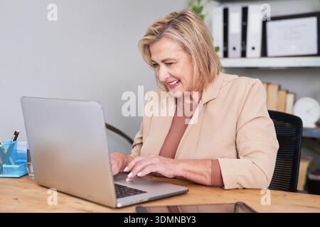 Professional Woman Working on Laptop at Office Desk in Office Setting Stock Photo