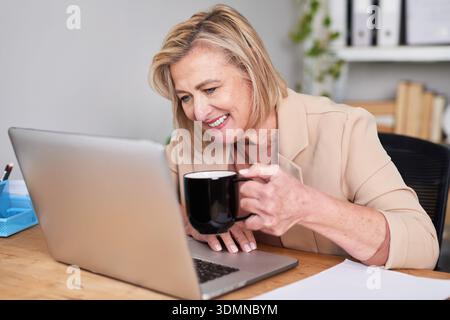 Professional Woman Works On Laptop At Office Desk With Coffee Mug Stock Photo