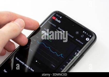 Hand holding a smartphone with YouTube Studio app opened, displaying channel analytics, views statistics and growth graph. Content creator dashboard i Stock Photo