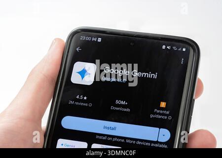Google Gemini app page on Google Play Store displayed on a smartphone screen, hand holding mobile device. Artificial intelligence AI assistant softwar Stock Photo