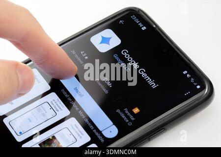 Man installing the Google Gemini AI assistant app on an Android smartphone, finger pressing install button on Google Play Store application page, mobi Stock Photo