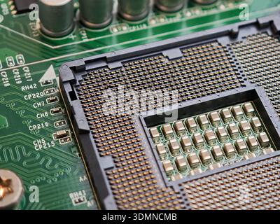 Macro closeup of open LGA CPU socket on green motherboard showing dense gold contact pins and a single bent pin, computer hardware damage and repair t Stock Photo