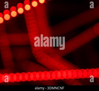 Abstract blurry red bokeh circle lights on black background, out of focus LED strips and glowing dots, shallow depth of field, night neon backdrop, co Stock Photo