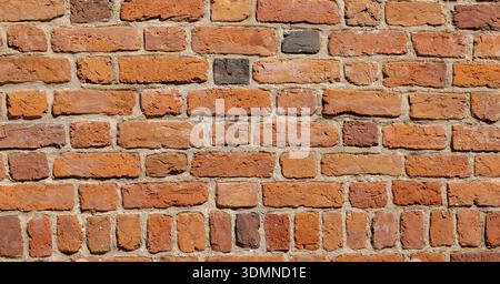 Old weathered red brick wall texture, rough masonry surface background, historic building facade detail. Construction material, orange clay bricks pat Stock Photo