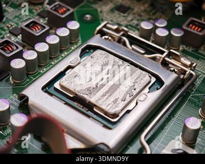 Dried cracked thermal paste on CPU in motherboard socket with cooler removed, macro closeup of computer processor and LGA bracket, repasting maintenan Stock Photo