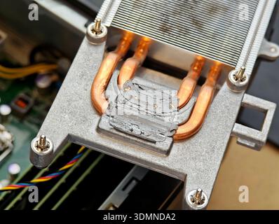 Dried cracked thermal paste on CPU cooler base with copper heatpipes, macro closeup of old heatsink removed for computer cleaning, maintenance repair Stock Photo