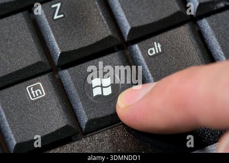Finger pressing Microsoft Windows 7 logo key on computer keyboard, closeup macro of button, laptop key, obsolete operating system upgrade update conce Stock Photo