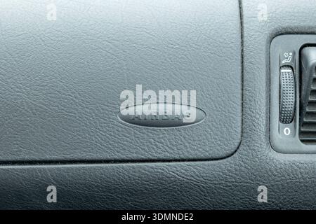 Passenger airbag label on car dashboard near vent control, SRS safety system symbol on the glovebox panel, automotive interior close up with textured Stock Photo