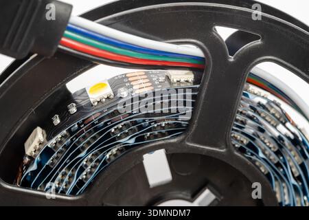 Extreme closeup macro detail of RGBW LED strip light roll with 5 pin connector cable and electronic components, flexible smart lighting tape coiled on Stock Photo