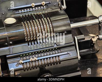 Vintage mechanical calculator and adding machine closeup, black metal counting device with numbered input levers and register wheels, retro office acc Stock Photo