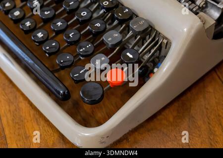 Extreme closeup of a vintage mechanical typewriter keys with bright red button and metal levers on wooden desk, retro writing and journalism conceptm, Stock Photo