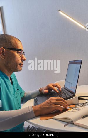Healthcare professional working on laptop, checking medical records Stock Photo