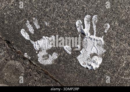 White painted handprints on rough asphalt surface, close-up Stock Photo