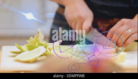 Hands slicing pale green veg on wooden board, with chef knife, ring, dark sweater, social overlays Stock Photo