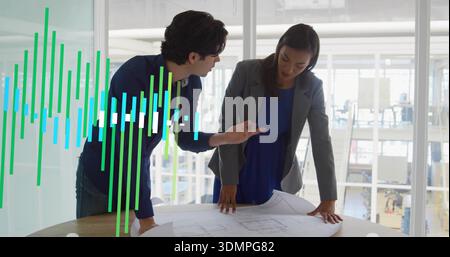 Pointing designers in dark top and blue dress studying blueprint in office with green glass overlay Stock Photo