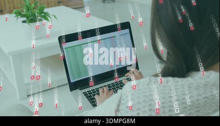 Typing Korean woman in pale sweater on couch using laptop spreadsheet with binary code and plant Stock Photo