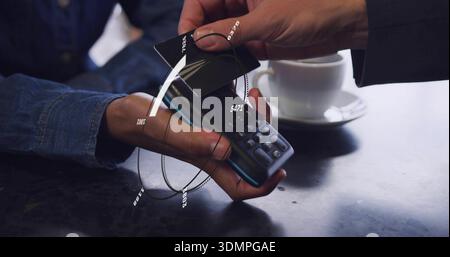 Tapping two hands' black card on reader at cafe table, denim sleeve, dark jacket, overlay, cup Stock Photo