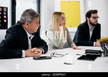 Team members attentively participating in a collaborative business meeting in a modern office setting Stock Photo