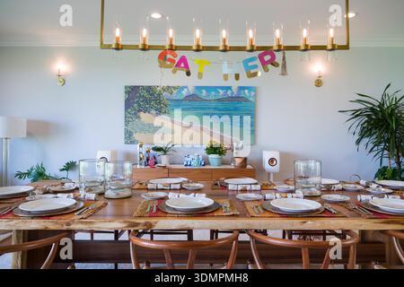 An elegantly set dining table is prepared for a Thanksgiving celebration within a well-lit American home. Stock Photo