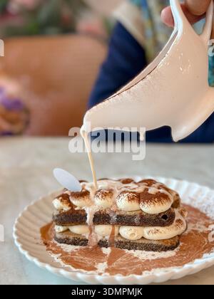 Close-up of tiramisu with sauce drizzle on white plate. Stock Photo