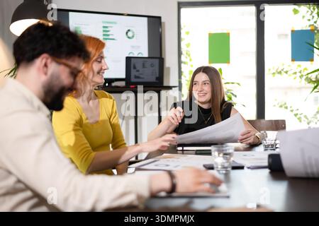 Business meeting with professionals discussing project plans and analyzing charts in a modern office setting during the afternoon Stock Photo