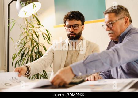 Business meeting with two professionals discussing documents in a bright office setting during the daytime Stock Photo