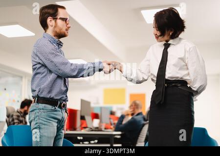 Business professionals collaborating in a modern office setting while shaking hands during a strategic meeting Stock Photo