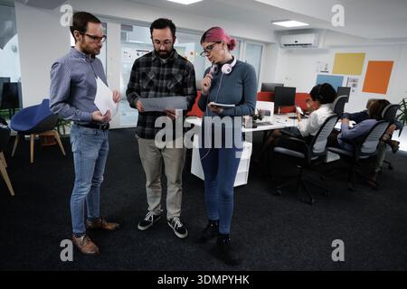 Business meeting in a modern office with diverse professionals discussing project details and collaborating during work hours Stock Photo