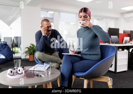 Business discussion between colleagues in modern office with casual seating during a brainstorming session over coffee Stock Photo