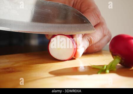 Cutting radish on a wooden board in bright kitchen Stock Photo