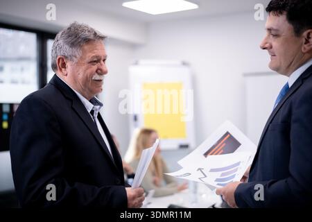 Professional business discussion during an office meeting between experienced colleagues showing collaborative teamwork and effective leadership in a Stock Photo