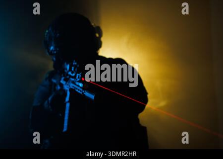 Silhouette of a tactical specialist with rifle and laser sight in dynamic lighting Stock Photo