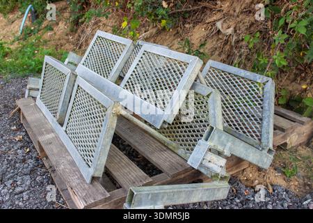 several galvanized metal mesh sections stacked on a wooden pallet outdoors. These industrial grates feature expanded metal diamond patterns. Stock Photo