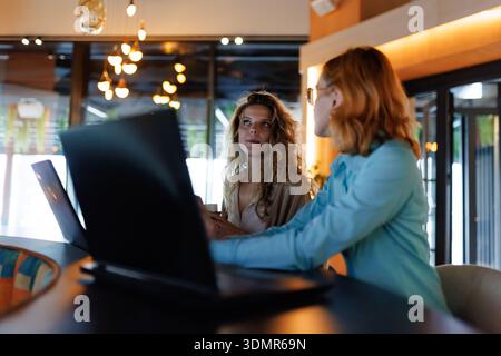 Engaging business discussion between two professional women in a modern office setting during the day Stock Photo