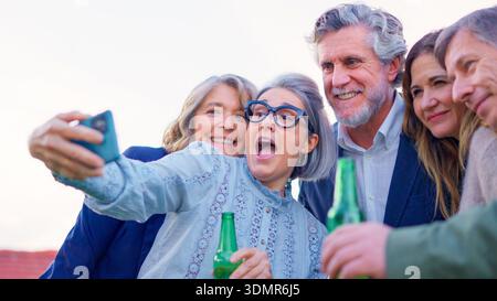 Mature friends drinking beer and taking a selfie outdoors Stock Photo