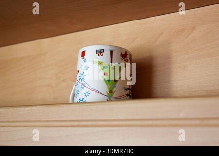 Beautiful small tea mug with Christmas print on the shelf. Stock Photo