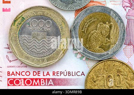 A macro closeup of various Columbia Peso bank coins on top of a paper bank note. Stock Photo