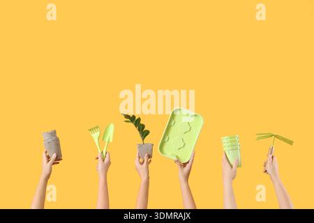 Female hands with gardening tools on yellow background Stock Photo