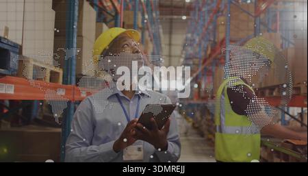 Inspecting manager wearing yellow hard hat and lanyard ID holding tablet in aisle, with AR graphic Stock Photo