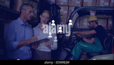 Reviewing staff in office attire checking clipboard in warehouse, forklift driver wearing helmet Stock Photo