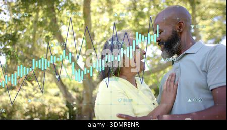 Embracing senior woman in yellow top and bearded man in gray polo beneath trees, financial overlay Stock Photo