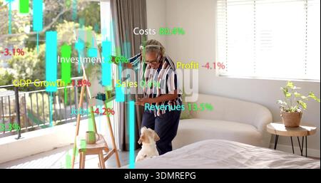 Petting small dog, senior woman wearing striped shirt using smartphone by bed with AR charts Stock Photo